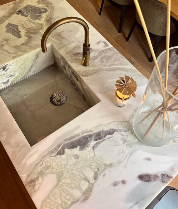 Marble countertop with brass faucet and vase.