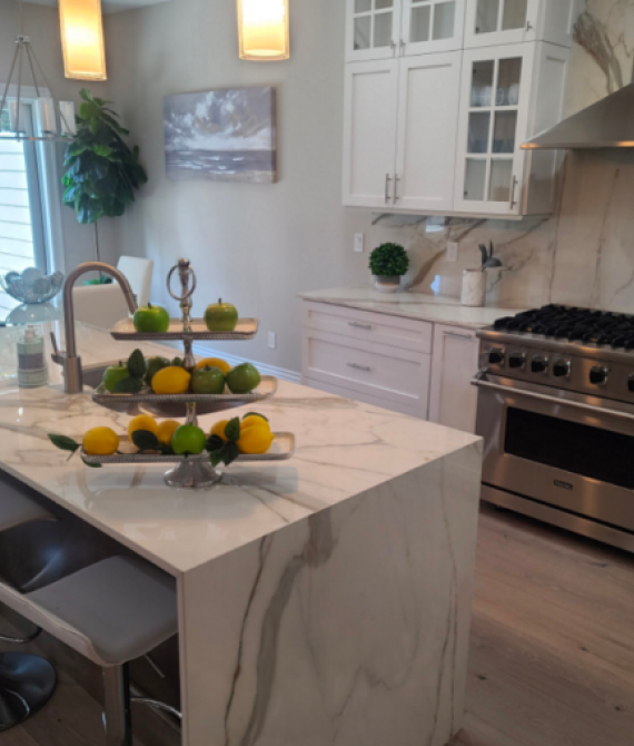 Modern kitchen with marble island and fruit.
