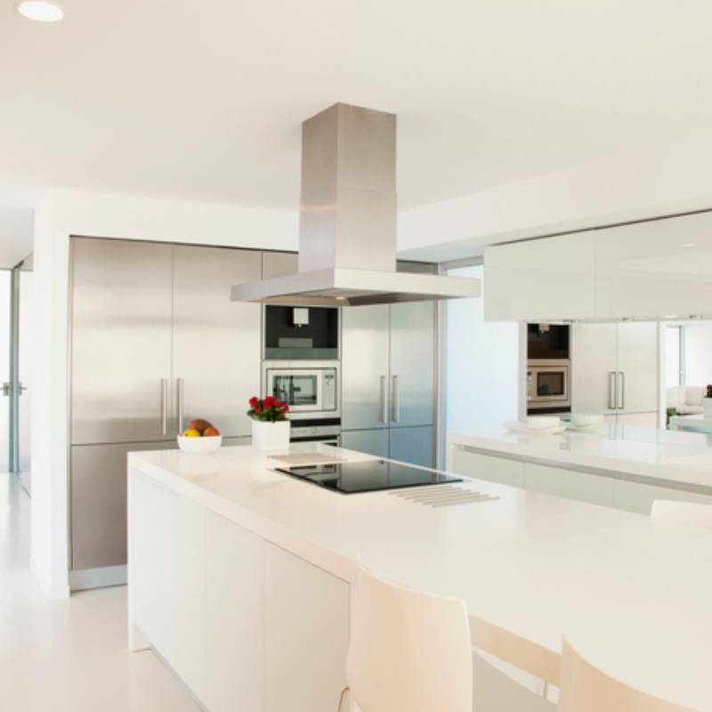 Modern white kitchen with sleek island and stainless steel appliances.