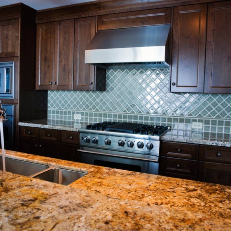 Modern kitchen with granite countertops and stainless steel stove.