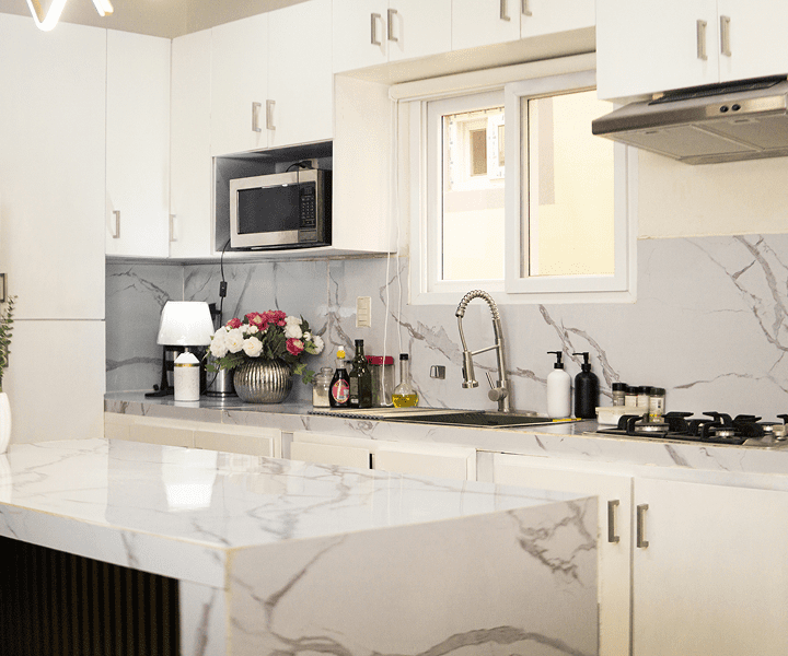 Modern kitchen with marble countertops and flowers.