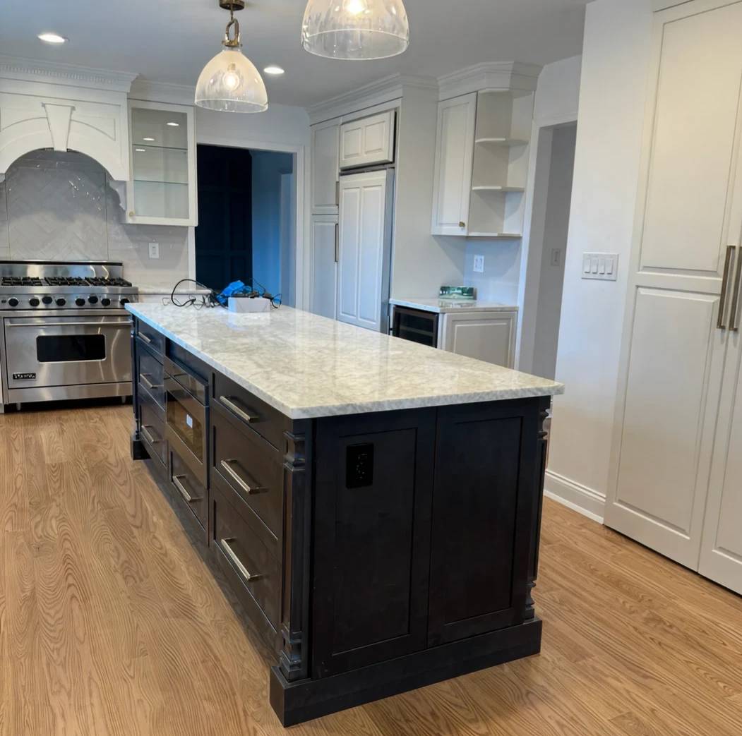 Modern kitchen with a large marble island and dark cabinetry.